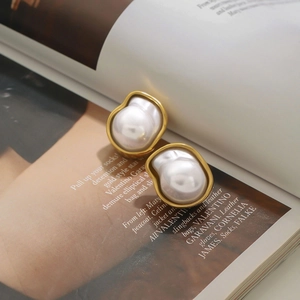 Baroque pearl earrings with golden metal frames resting on a fashion magazine