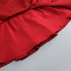 Detailed close-up of red off-shoulder dress featuring intricate hollow embroidery lace