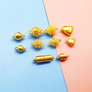 Detailed view of various golden magnetic jewelry clasps in heart, sphere, and cylinder shapes