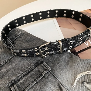 Detail of Y2K vintage black denim belt with double-prong buckle and silver star rivets