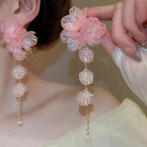 Detail of pink acrylic flower earrings with long tassels on a model showing shimmer finish