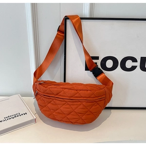 Close-up of orange quilted crossbody bag with adjustable wide strap and silver zipper