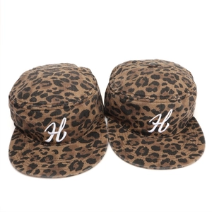 Dettaglio di cappelli militari leopardati con ricamo della lettera H bianca su cotone