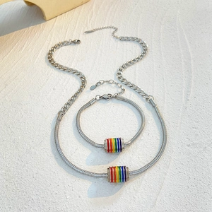 Detail of silver chain jewelry set featuring cylindrical rainbow striped pendants