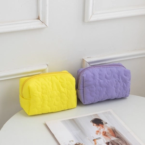 Detail of quilted floral patterns on large yellow and purple cosmetic storage bags