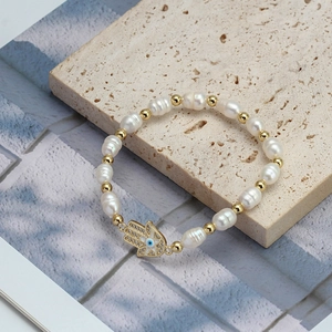 Close-up of baroque pearl bracelet with Hamsa Hand charm and blue evil eye detail