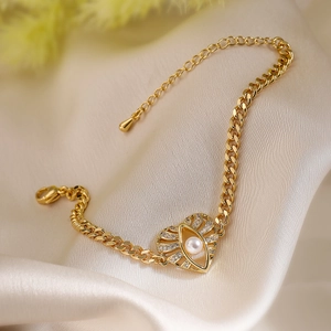 Gold plated evil eye bracelet with heart charm and pearl on elegant silk background