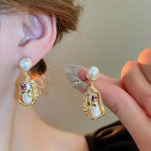 Detail of vintage gold rose earrings with pearls and purple enamel on a model