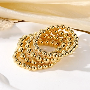 Punk style multi-layer gold bead chain bracelet set on white dish and beige fabric