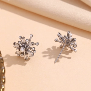 Macro detail of silver firework earrings with white pearls and baguette zircon stones