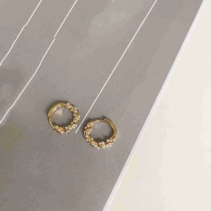 Elegant gold twist hoop earrings with inlaid pearls on a minimalist grey card background