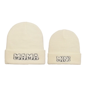 Dettaglio di berretti in maglia bianco crema con ricamo MAMA e MINI per genitore e figlio