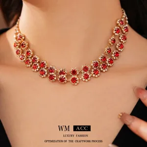 Elegant double-layered gold necklace featuring red round gemstone floral pendant on model