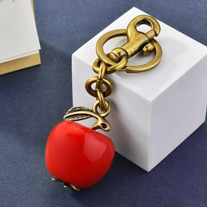 Red apple keychain with vintage bronze hardware on white geometric cube display