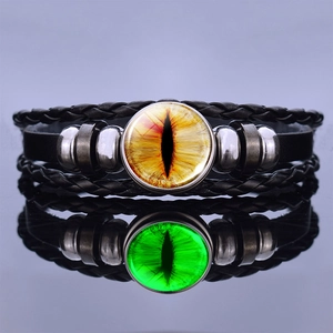Macro shot of steampunk dragon eye leather bracelet with a glowing glass cabochon focal point