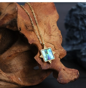 Macro detail of vintage 18K gold plated square necklace with iridescent abalone shell