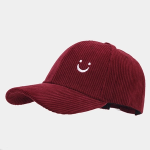 Dettaglio del cappello bordeaux in velluto a coste con ricamo smiley e texture a costine
