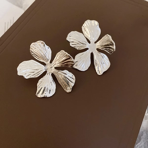 Macro detail of silver metal flower earrings featuring realistic wrinkled petal textures