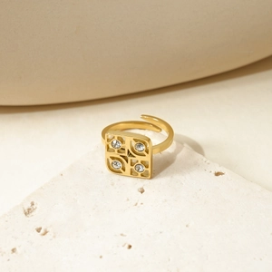 Elegant gold square hollow ring with four zircon stones on a decorative stone base