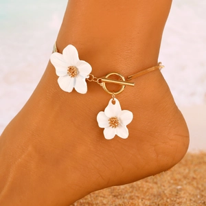 Golden ankle chain with white floral pendants on beach, summer vacation jewelry style