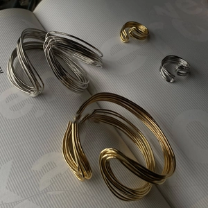 Artistic close-up of twisted metal rings and bracelets in gold and silver finish on a book
