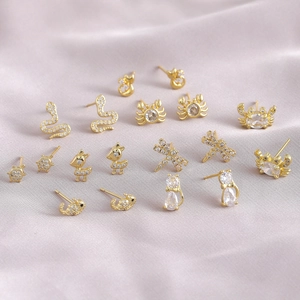 Golden animal-shaped stud earrings with sparkling cubic zirconia on purple satin