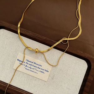 Elegant gold snake chain necklace with polished sphere slider on textured wood tray