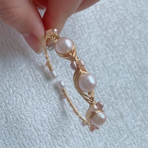 Macro detail of wire-wrapped freshwater pearls on a golden handcrafted bracelet