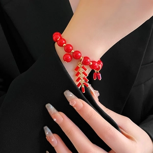 Gros plan d'un bracelet de perles rouges avec pendentif de fête sur le poignet d'un mannequin