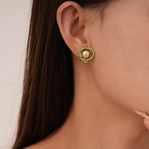 Vintage gold hoop earrings with green rhinestones and pearls worn by a model