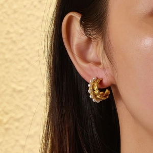 Detail of 18k gold stainless steel earrings with white pearls and embossed hearts