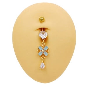 Détail du piercing de nombril fleur avec zircons bleus et clairs sur métal doré