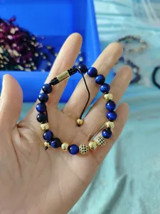 Detailed shot of 8mm blue tiger eye beads and pavé crystal charms on braided bracelet