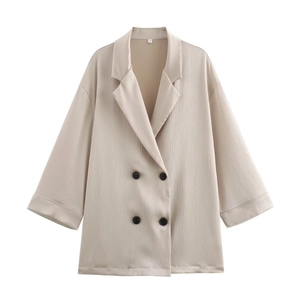 Détail d'un blazer croisé beige en tissu plissé texturé avec boutons foncés