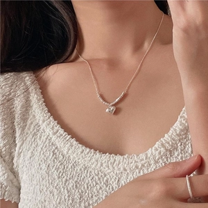 Close-up of a 925 sterling silver heart necklace and matte ring worn by a model