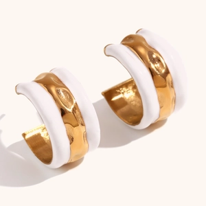 Macro detail of wave texture on gold-plated hoop earrings with white enamel finish