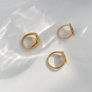 Three-piece set of gold rings with a sunburst relief and polished seal design