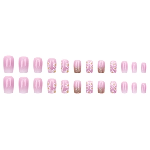 Pink gradient press-on nails with white daisy floral patterns and golden glitter accents