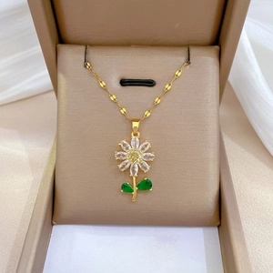 Macro detail of sunflower pendant with yellow zircon and green leaf on gold chain
