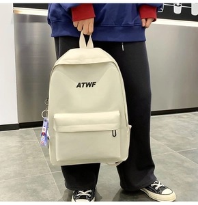 Close-up of minimalist off-white canvas backpack held by hand with front zipper detail