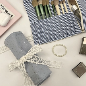 Detail of blue star pattern makeup brush roll bag with white lace ribbon and stripes
