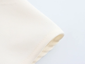 Gros plan détaillé de la texture du tricot beige et des coutures de l'ourlet de la robe