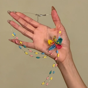 Hand-held close-up of a colorful beaded necklace with a large handmade flower detail.