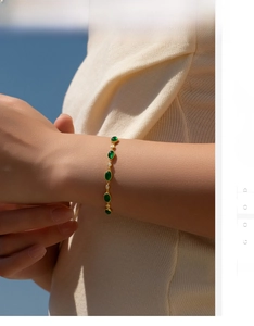 Close-up of vintage gold bracelet with oval emerald green stones on woman's wrist