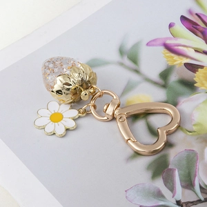 Detailed view of golden strawberry keychain with daisy charm and heart-shaped ring