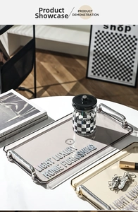 Detail of a smoky gray acrylic tray with silver handles and checkerboard jar décor
