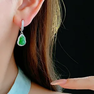 Elegant silver earrings with green drop gemstone and zircon accents on model