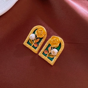 Detail of vintage gold arch earrings with green enamel and yellow rose flower decor