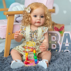 Realistic 55cm rebirth baby doll with curly hair wearing floral outfit and beige overalls