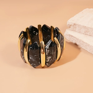 Détail des cubes en résine de marbre noir et des piliers en métal doré sur le bracelet